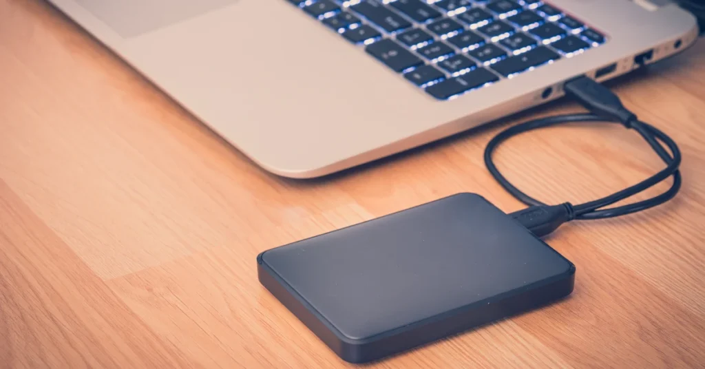 قرص تخزين خارجي موصول بحاسوب محمول عبر USB.