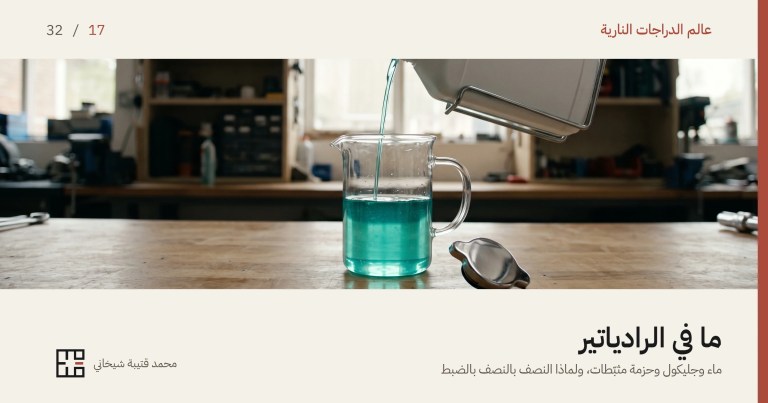 غلاف مقال سائل تبريد الدراجة النارية: إبريق زجاجي شفّاف على طاولة عمل خشبية نصفه مملوء بسائل تبريد أزرق مخضرّ شفّاف يمرّ فيه الضوء، وفوقه زجاجة بيضاء بلا ملصق مائلة في حمّالة معدنية تصبّ خيطاً رفيعاً من السائل في الإبريق، وإلى جانبه غطاء رادياتير معدني بأذنَين ملقى على جنبه، وخلفهما رفوف ورشة خارج التركيز.