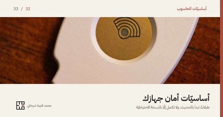 غلاف مقالة أساسيّات أمان جهازك: صورةٌ مقرّبة لمفتاح أمانٍ أبيض صغير على خشبٍ داكن، في وسطه قرصٌ ذهبيّ يُلمس عند تسجيل الدخول. وفوق الصورة اسم السلسلة «أساسيّات الحاسوب» والرقم 32 من 33، وتحتها العنوان «أساسيّات أمان جهازك» وسطرٌ يقول: طبقاتٌ تبدأ بالتحديث، ولا تكتمل إلّا بالنسخة الاحتياطيّة.