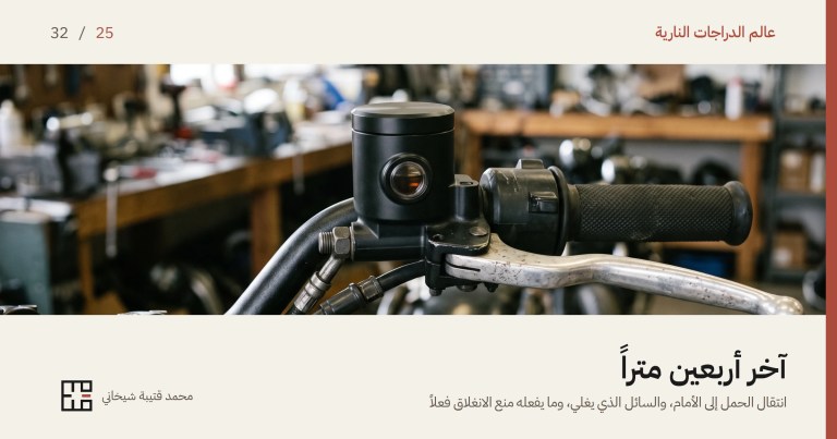 الأسطوانة الرئيسية لفرملة دراجة نارية أمامية مثبَّتة على المقود في ورشة: جسم أسود بغطاء مسطّح، وفي جانبه نافذة زجاجية صغيرة يظهر منها سائل بلون العنبر ومستواه، وإلى جانبها مجموعة المفاتيح ومقبض الفرملة المعدنيّ والقبضة المحزّزة، وخلفها منضدة عمل غير واضحة.